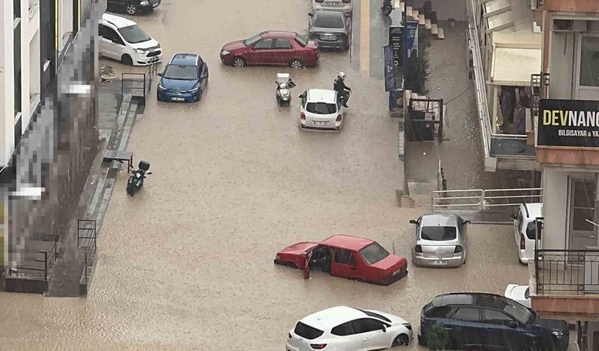 Yağmurda mahsur kalan motosikletli çareyi otomobilin üzerine çıkmakta buldu